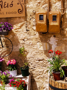 Crete island, Greece. Beautiful flowers in the charming small village of Amnatos, near Rethymnon. Plants arranged in a quirky, engaging way making use of brightly painted everyday objects. Summer day.