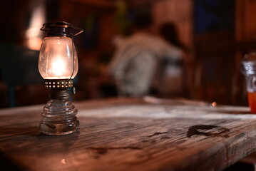 A vintage oil lamp glowing on a wooden table at night