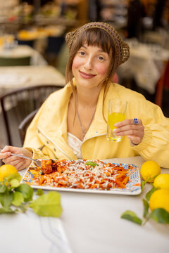Fototapeta A smiling woman enjoys a traditional Pasta alla Norma at an outdoor restaurant in Sicily. The image conveys joyful travel, local cuisine, and authentic Mediterranean lifestyle, ideal for food, tourism