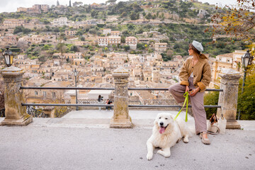Woman with large white dog enjoys the panoramic view over Modica, Sicily. A perfect moment of...