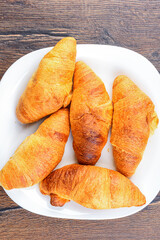 Top view of freshly baked croissants on white plate.