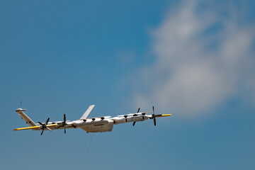 Close up of a drone in flight isolated against a blue sky with copy space