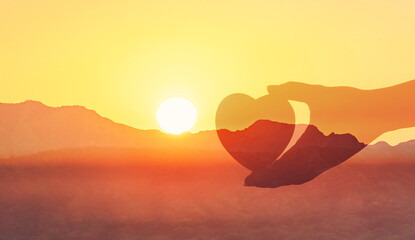 Hand holding  heart on beautiful golden sunset nature background.

