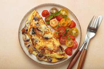 Mushroom omelette with cherry tomato salad on the side, served on a plate. Healthy breakfast or lunch top view