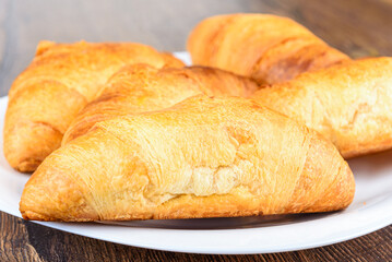 Selective focus on freshly baked croissants on a white plate.