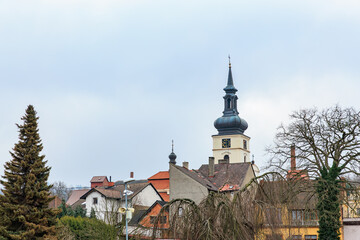 Historic church tower and village rooftops under overcast sky