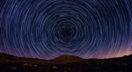 Fototapeta premium Celestial Trails Night Sky - Star trails create mesmerizing circular patterns above a dark landscape, symbolizing eternity, the cosmos, time, rotation, and wonder