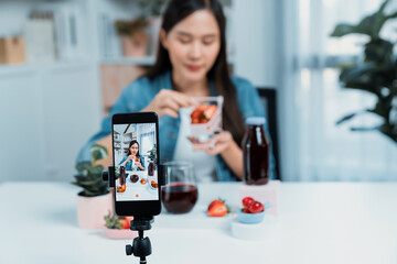 Selective focus smartphone with smiling young beautiful Asian reviewing mixed strawberry and cherry...