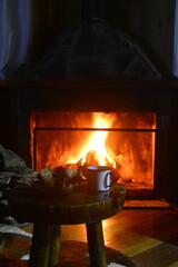 Caneca esmaltada com caf&eacute; em frente a uma lareira numa cabana nas montanhas