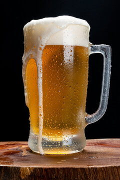 Caneca de chopp com espuma caindo sobre copo gelado