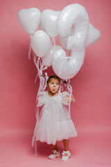 Fototapeta premium little girl with balloons and the number three on a pink background celebrates her birthday in the studio