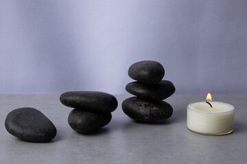 Calm and soothing arrangement of black stones and a flickering candle in a serene setting
