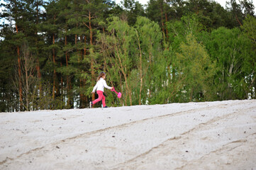 Happy child girl playing and running with shovel in her hand on the sand on nature background. Happy childhood concept
