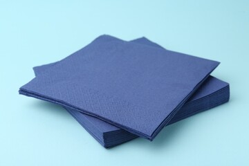 Stack of disposable paper handkerchiefs on light blue background, closeup