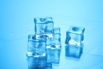 Cubes of clear ice on light blue background, closeup