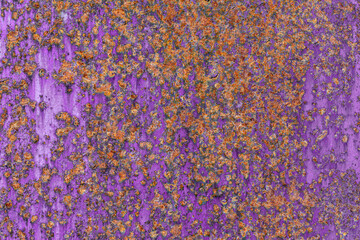Close-up of a corroded purple-painted metal surface with heavy orange rust, creating a vibrant and...