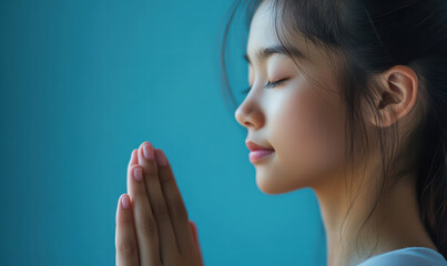 Inner Serenity: A young woman embodies tranquility, her eyes closed, hands clasped, revealing a moment of peaceful contemplation and focused meditation.