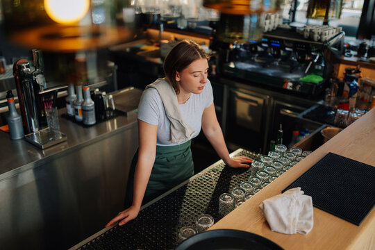 Tired bartender leaning on bar counter in empty pub
