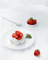 french pavlova dessert on a white plate with red strawberries on a white background