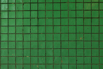 Close-up of a green ceramic tiled wall with visible grout lines and minor surface imperfections, ideal for backgrounds or design elements.
