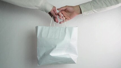 Close-up of a man's hand handing a package or a bag to a woman's hand. Concept - door-to-door delivery, goods delivery, food delivery, logistics, courier, courier services.