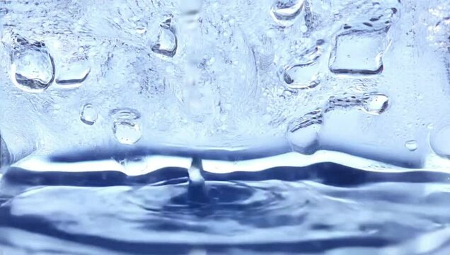 Clear water droplets splashing in calm blue water surface  