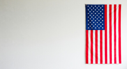 American flag hanging on white wall in simple indoor setting  
