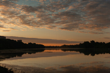A sunrise over a tranquil summer lake, dark photo