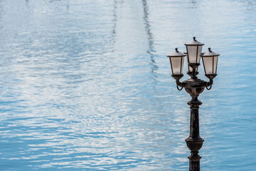 Typical retro street lamp with blue sea calm water on background on the seafront in Bari, Italy. Copy space