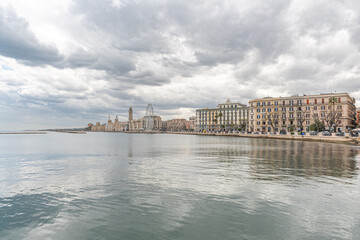 Panorama of Bari, Puglia or Apulia, southern Italy with Mediterranean Sea, street lamps, ferris wheel and fascist architecture on the seafront promenade with storm clouds