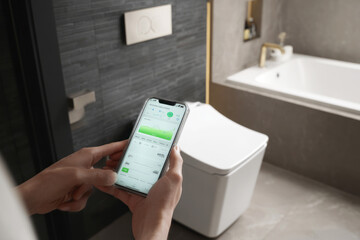 Person holding smartphone with smart toilet app displaying nutrient analysis, inside modern bathroom with sleek fixtures and minimalist design. ai generative