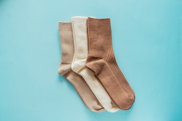Three pairs of cozy socks in beige colors arranged neatly on soft blue background, showcasing texture and design for fashion and comfort enthusiasts