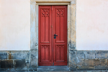 Rustic red wooden door with stone surround on weathered wall