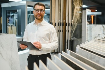 Shop assistant taking notes on clipboard in ceramic tile store