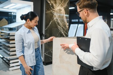 Salesman showing ceramic tile to woman in store