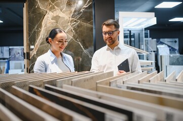 Woman choosing ceramic tiles with shop assistant advising her