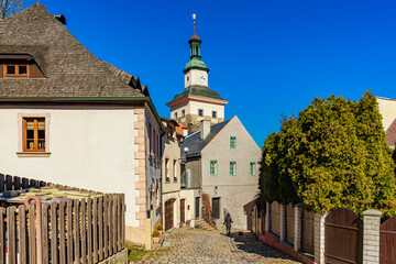 Cobblestone path leading to historic european tower under clear blue sky