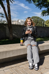 Young woman using smartphone outdoors with reusable water bottle