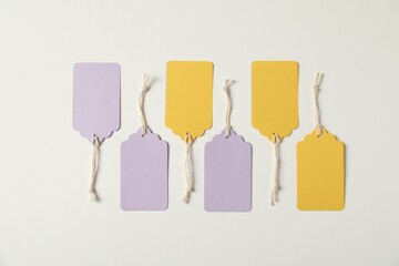Blank tags with strings on white background, flat lay