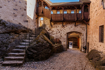 Medieval stone castle courtyard with stairway and wooden balcony