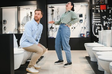 Obraz premium Couple having fun choosing toilet in bathroom fixtures store