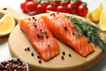 Seafood. Pieces of salmon fillet, spices, tomatoes and lemon wedges on table, closeup