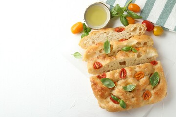 Cut delicious focaccia with tomatoes, basil and oil on light table, flat lay. Space for text