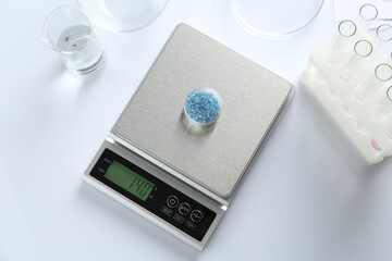 Scale with Petri dish of sample and other laboratory equipment on white background, flat lay