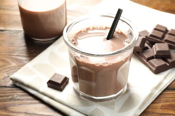 Chocolate milk in glass and ingredient on wooden table, closeup