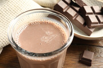 Chocolate milk in glass and ingredient on wooden table, closeup