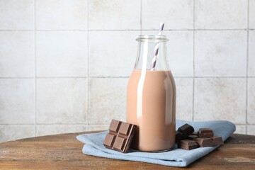 Chocolate milk in glass bottle and ingredient on wooden table, space for text