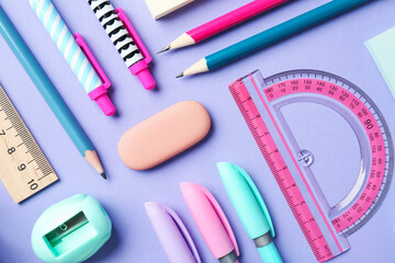 Pens and other stationery on violet background, flat lay