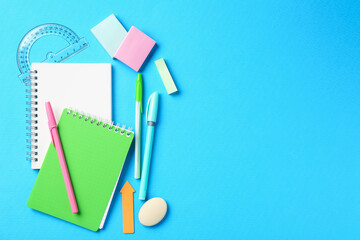 Pens and other stationery on light blue background, flat lay. Space for text