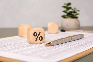 Wooden cube with percentage sign on financial document.